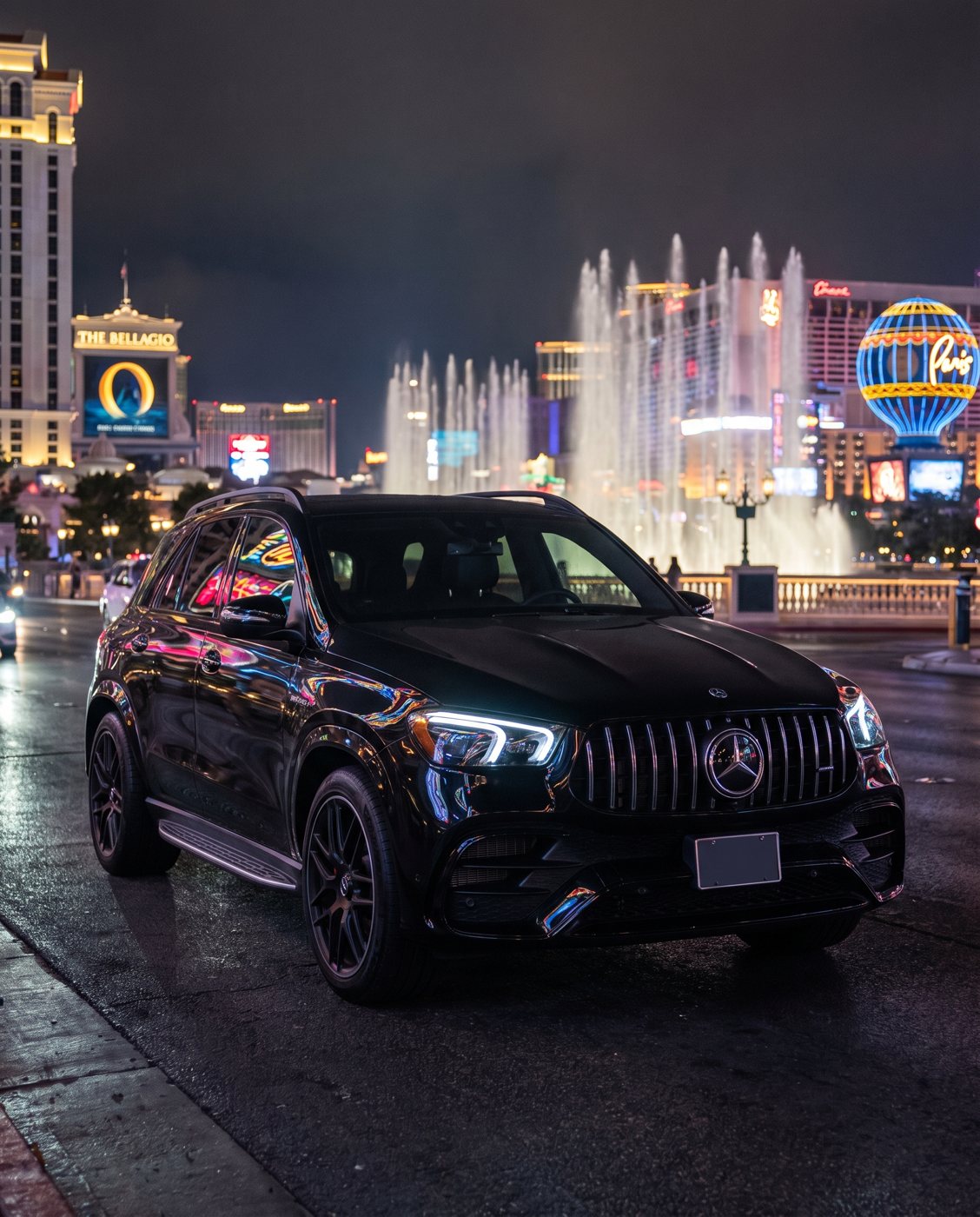 Black SUV on a neon-lit boulevard at night